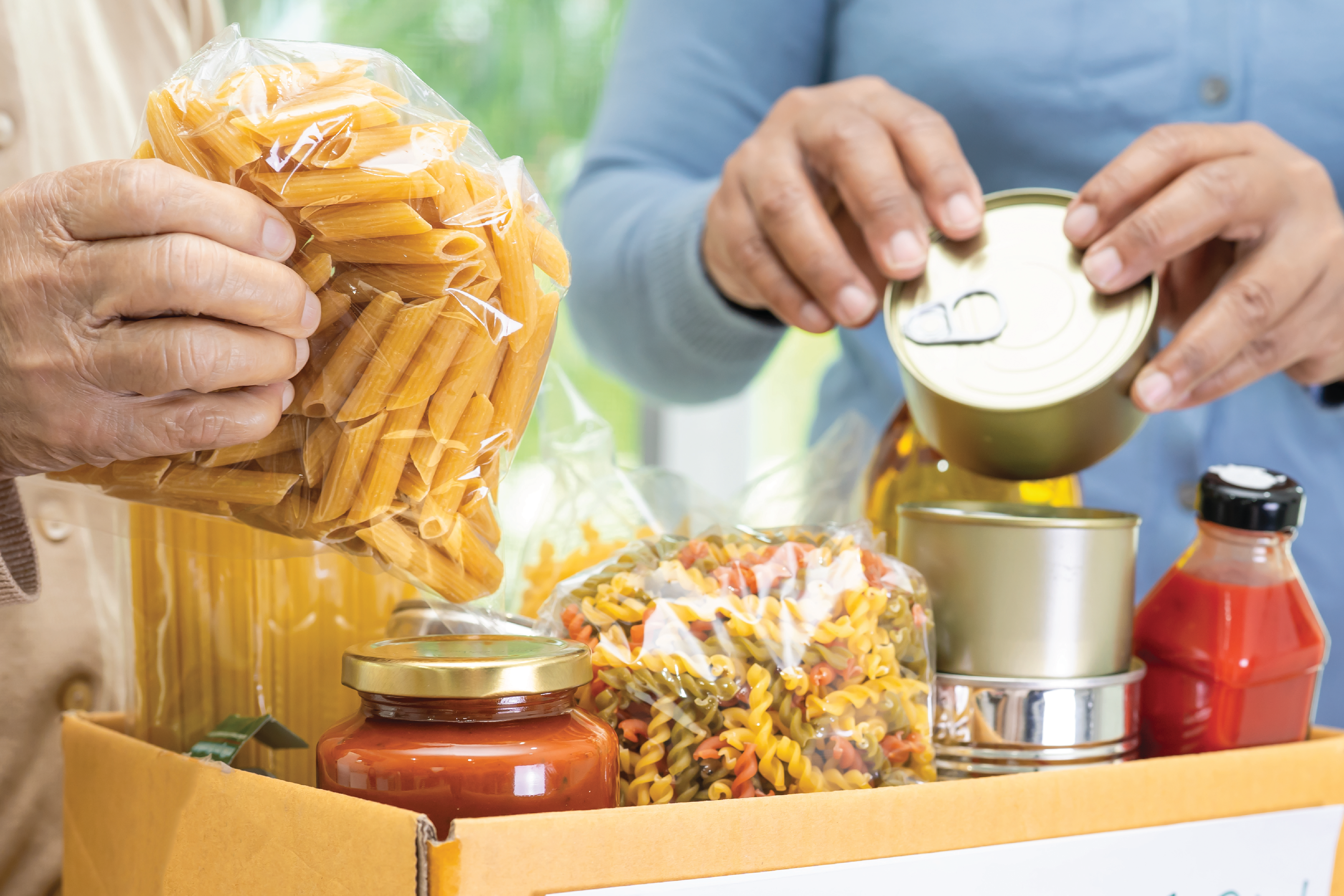 Image of two people holding non-perishableitems from a food donation box