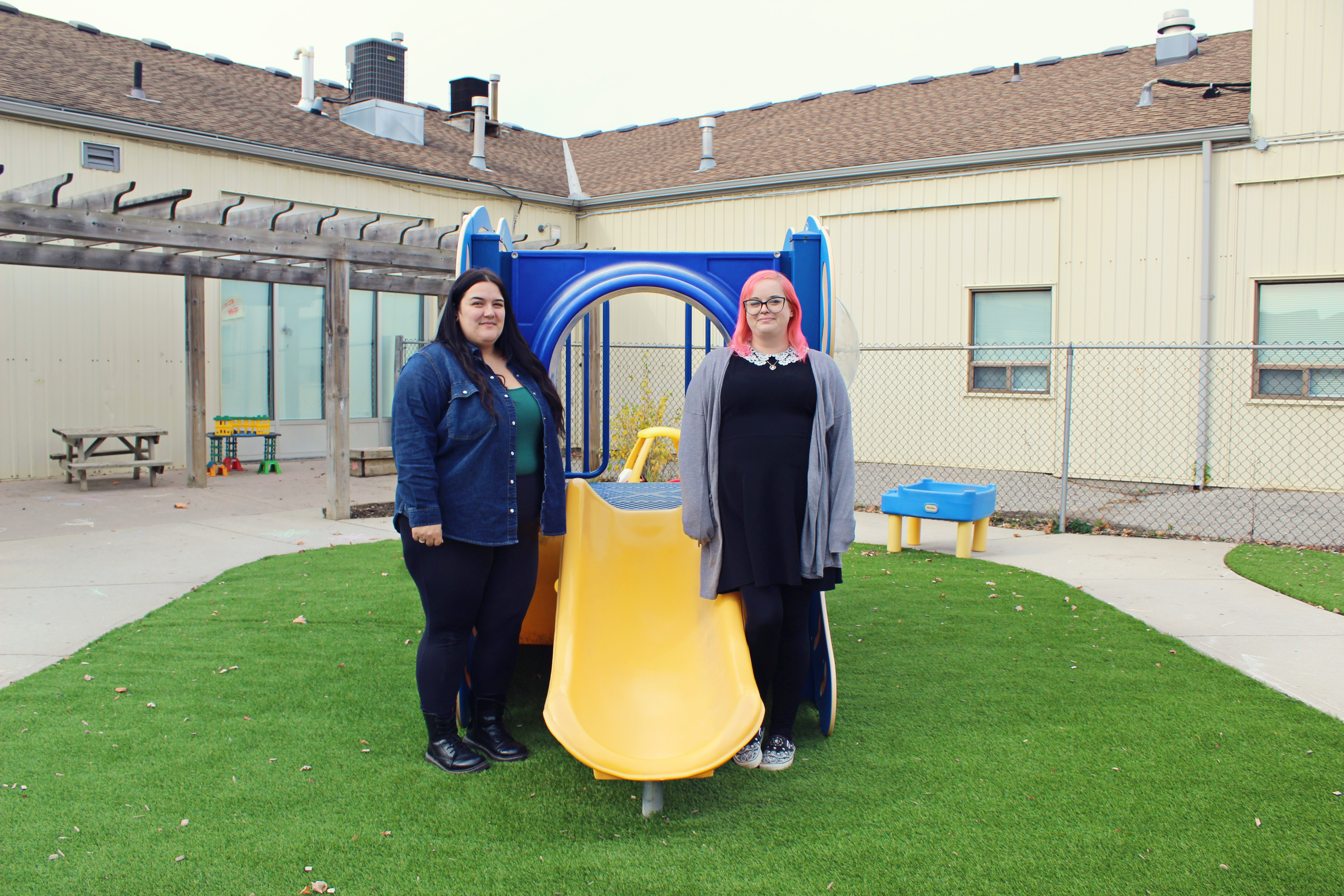 Two Early Childhood Educators standing in a playground