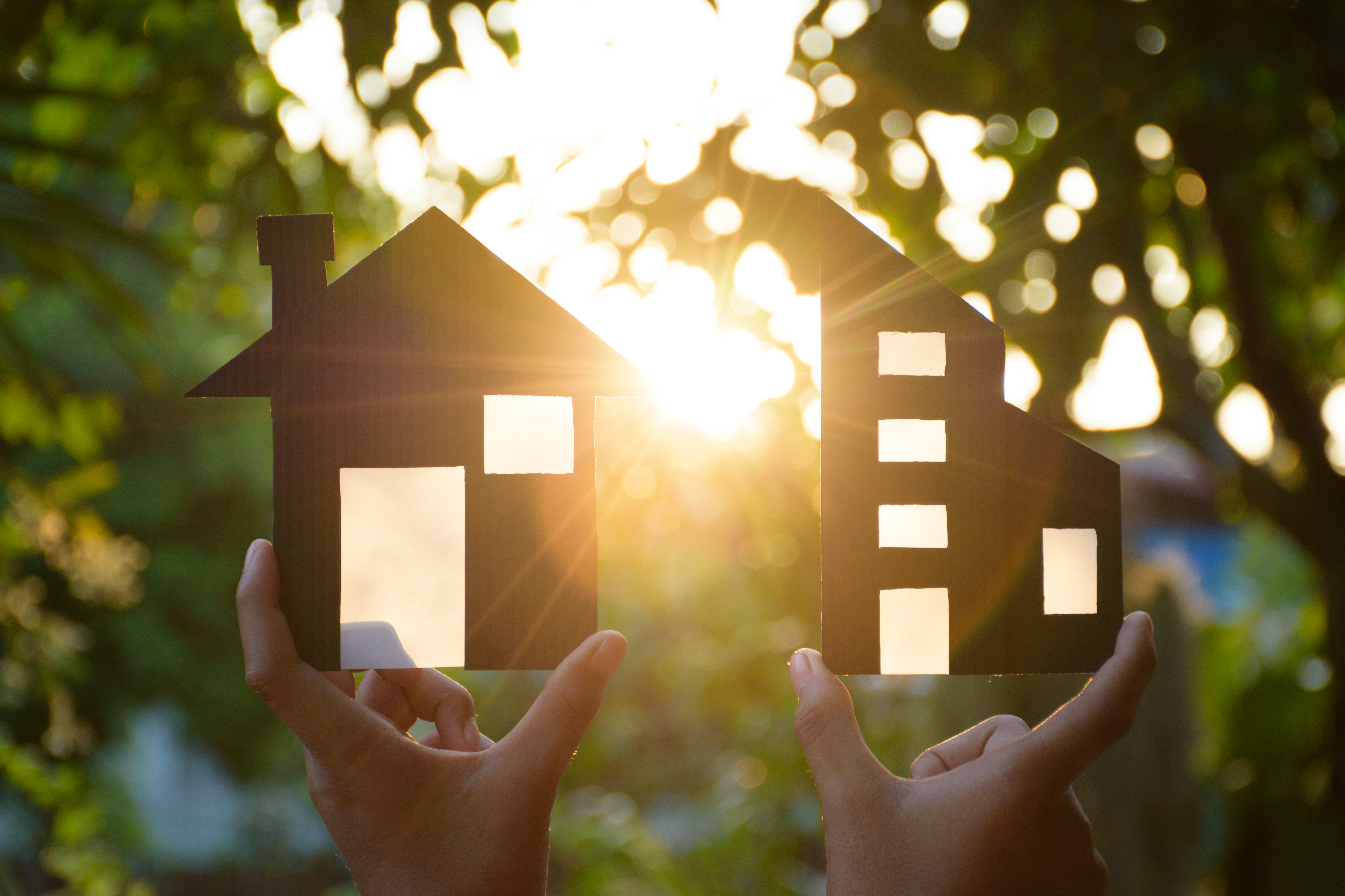 Two Hands Holding Black Miniature Models of Houses