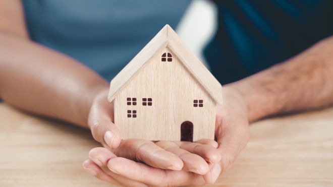 Hands holding wooden house 