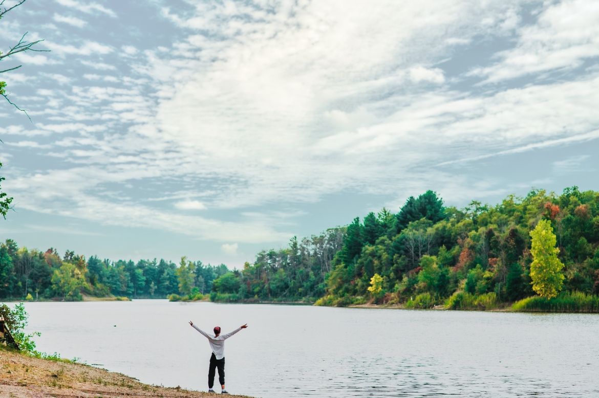 Woman with arms raised looking at a lake