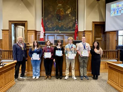 Image inside Council Chambers of Warden Brian Ropp with several students